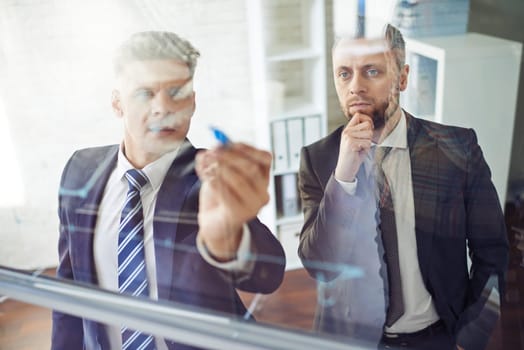 Male employee explaining graph on transparent board