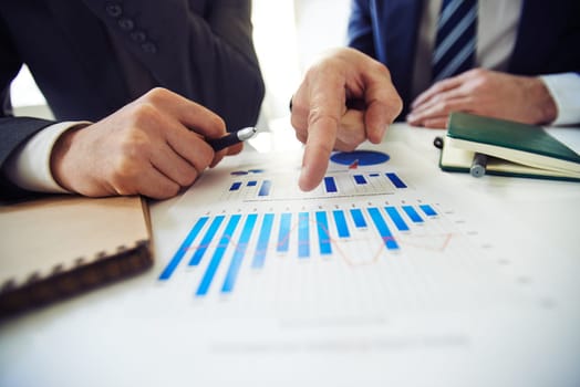 Two businessmen discussing chart while one of them pointing at it