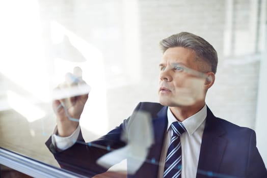 Modern businessman standing by transparent board