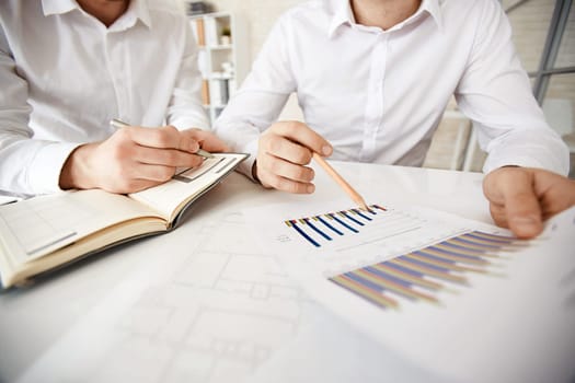 Group of businessmen explaining chart and making notes
