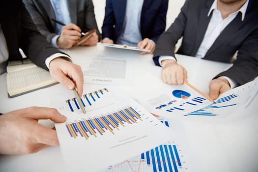 Two co-workers pointing at charts while comparing them