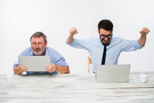 The two colleagues working together at office on white  background. both are looking at the computer screens. Both surprised. concept of positive emotions and good news