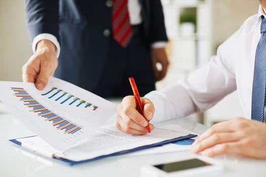 Employee giving document to boss while he signing contract