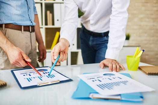 Male employees discussing business document in office