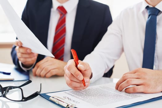 Businessman with pen over contract reading it