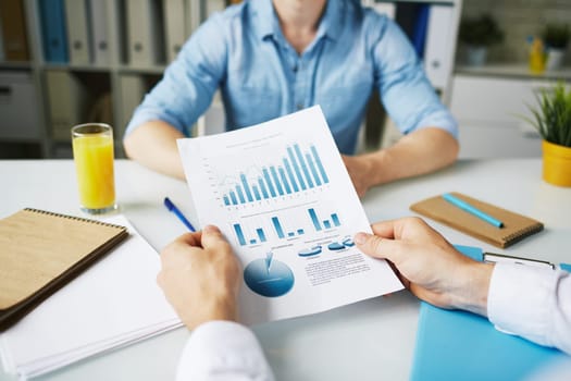 Businessman holding document with data in working environment