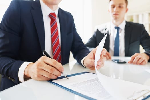 Businessman signing contract with his partner near by