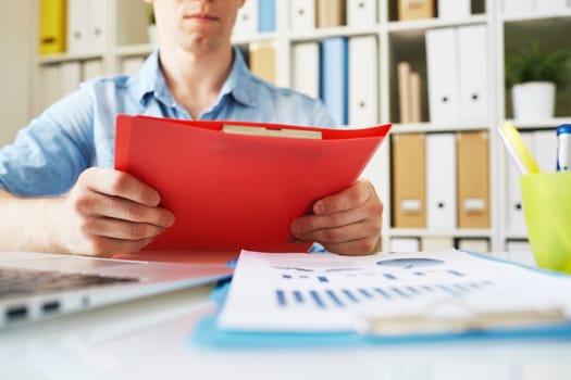 Businessman holding red folder over workplace