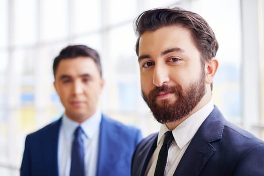 Confident businessman looking at camera on background of his colleague