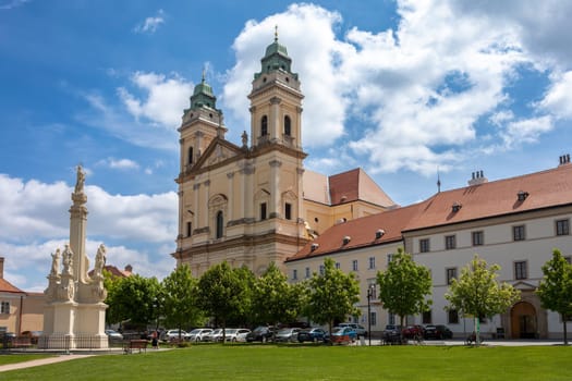 VALTICE, CZECH REPUBLIC - MAY 7th 2023: Baroque church of the Assumption of the Virgin Mary at Freedom Square at sunny summer day, UNESCO world heritage, popular travel destination