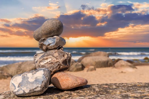Stone pyramids on the dreamy Baltic Sea sandy beach on Rügen to the spectacular orange sunset