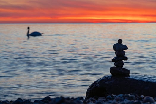 Stone pyramids on the dreamy Baltic Sea sandy beach on Rügen to the spectacular orange sunset