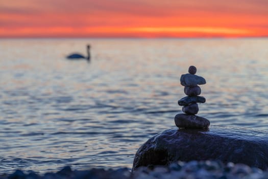 Stone pyramids on the dreamy Baltic Sea sandy beach on Rügen to the spectacular orange sunset