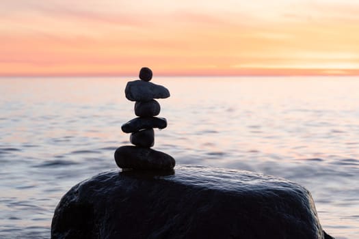 Stone pyramids on the dreamy Baltic Sea sandy beach on Rügen to the spectacular orange sunset