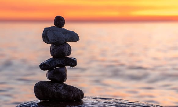 Stone pyramids on the dreamy Baltic Sea sandy beach on Rügen to the spectacular orange sunset