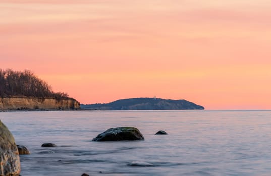 magnificent Baltic Sea coast on the island of Rügen with a view of Hiddensee to the orange sunset