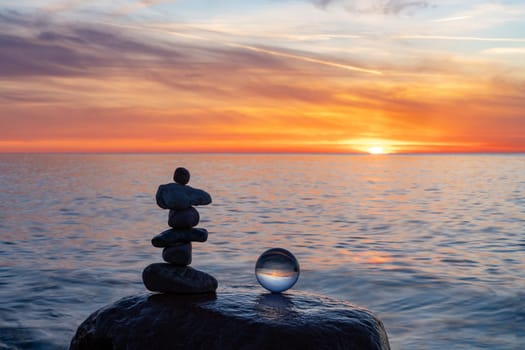 Stone pyramids and glass sphere on the dreamy Baltic Sea sand beach on Rügen to the spectacular orange sunset