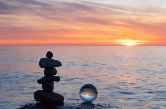 Stone pyramids and glass sphere on the dreamy Baltic Sea sand beach on Rügen to the spectacular orange sunset