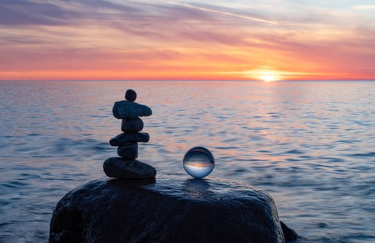 Stone pyramids and glass sphere on the dreamy Baltic Sea sand beach on Rügen to the spectacular orange sunset