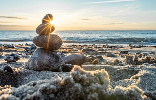 Stone pyramids on the dreamy Baltic Sea sandy beach on Rügen to the spectacular orange sunset