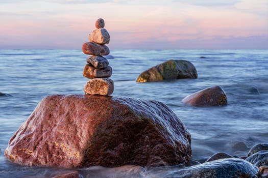 Stone pyramids on the dreamy Baltic Sea sandy beach on Rügen to the spectacular orange sunset