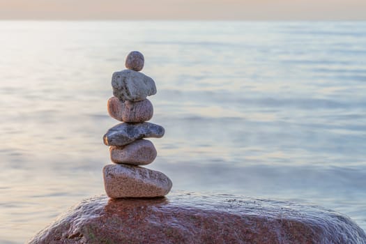 Stone pyramids on the dreamy Baltic Sea sandy beach on Rügen to the spectacular orange sunset