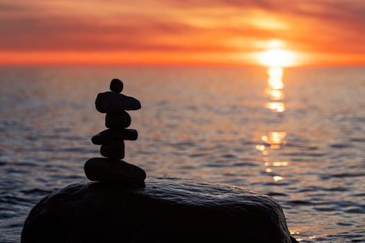 Stone pyramids on the dreamy Baltic Sea sandy beach on Rügen to the spectacular orange sunset