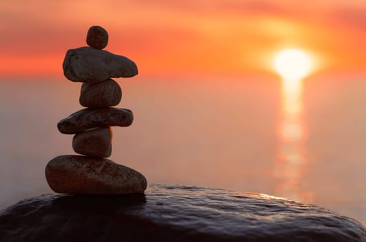 Stone pyramids on the dreamy Baltic Sea sandy beach on Rügen to the spectacular orange sunset