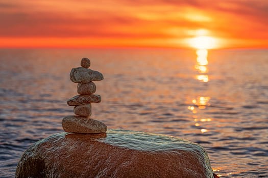 Stone pyramids on the dreamy Baltic Sea sandy beach on Rügen to the spectacular orange sunset