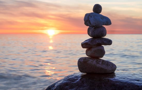 Stone pyramids on the dreamy Baltic Sea sandy beach on Rügen to the spectacular orange sunset