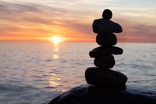 Stone pyramids on the dreamy Baltic Sea sandy beach on Rügen to the spectacular orange sunset