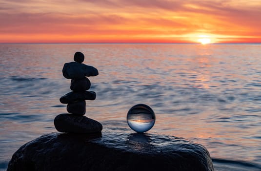 Stone pyramids and glass sphere on the dreamy Baltic Sea sand beach on Rügen to the spectacular orange sunset