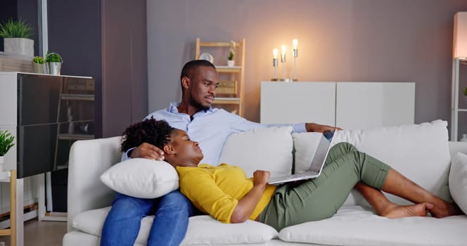 Young Couple Using Laptop On Couch At Home