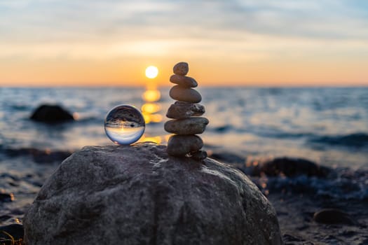 Stone pyramids and glass sphere on the dreamy Baltic Sea sand beach on Rügen to the spectacular orange sunset