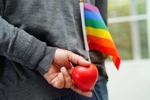Asian woman holding red hert with rainbow flag, LGBT symbol rights and gender equality, LGBT Pride Month in June.