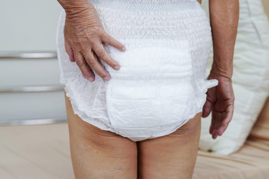 Asian elder senior woman patient wearing adult incontinence diaper pad in hospital.