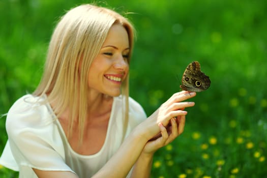 Woman playing with a butterfly on green grass