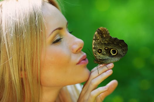 Woman playing with a butterfly on green grass