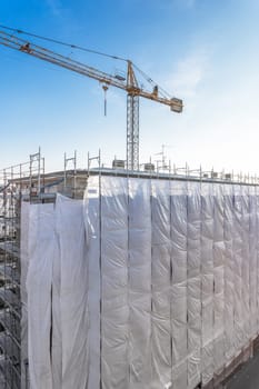 Extensive scaffolding providing platforms for work in progress on a new apartment block, Tall building under construction with scaffolding, New construction site.