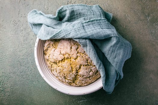 Homemade spelt bread with herbs and wild garlic, process of raising dough in a special basket. Dough made from natural sourdough, fermentation process