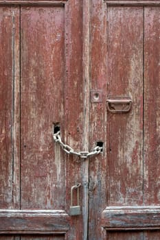 Old rough wooden door with bolts and padlocks. Details of iron and wood.