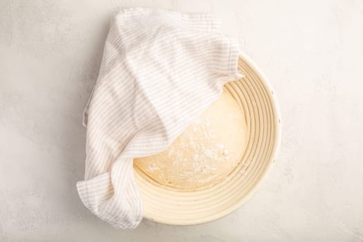 Raw yeast dough resting and rising in a special basket on kitchen table