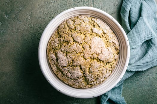 Homemade spelt bread with herbs and wild garlic, process of raising dough in a special basket. Dough made from natural sourdough, fermentation process