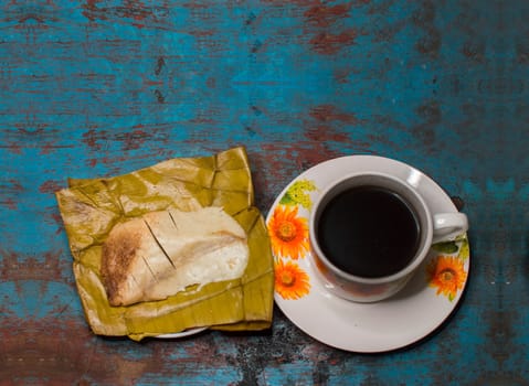 Traditional Stuffed Pisque Tamal with cup of coffee served on wooden table, Central American typical food Stuffed Tamal Pisque, Stuffed tamale with cup of coffee served on wooden table