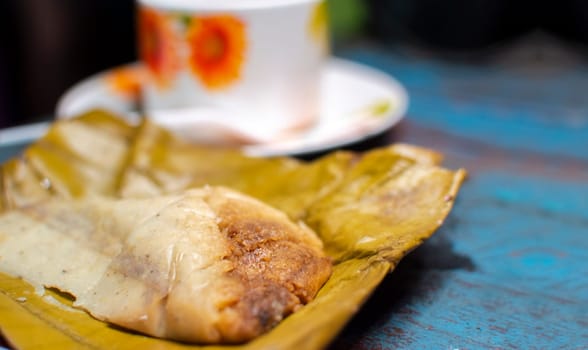 Stuffed tamale served on wooden table, stuffed tamale on banana leaf served on wooden table, typical nicaragua food