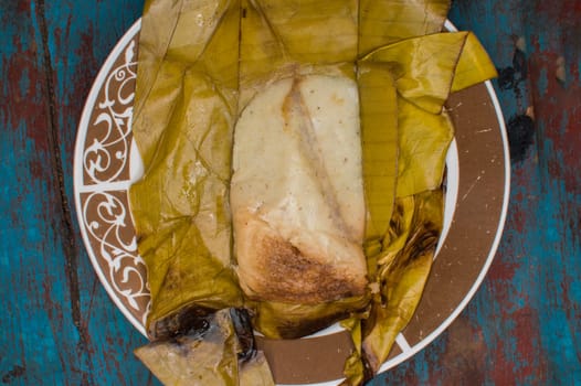 Traditional Tamal Pisque stuffed in banana leaf served on wooden table, Central American typical food Tamal Pisque stuffed. Stuffed tamale served on wooden table