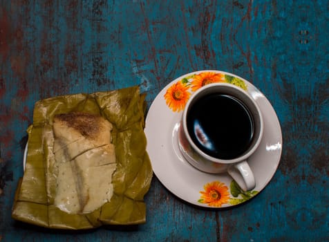 Stuffed tamale with cup of coffee served on wooden table, Traditional Stuffed Pisque Tamal next to cup of coffee served on wooden table, Central American typical food Stuffed Tamal Pisque