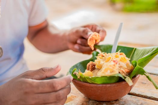 Close-up of person eating vigoron on table. Local person eating a traditional vigorón. The vigoron typical food of Granada, Concept of typical food of Nicaragua