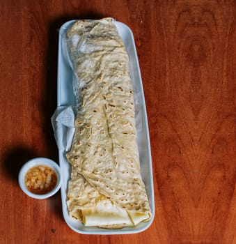 Top view of Nicaraguan Quesillo on a plate served on wooden table. Delicious traditional Nicaraguan quesillo served on wooden table, View of a Nicaraguan quesillo served on table