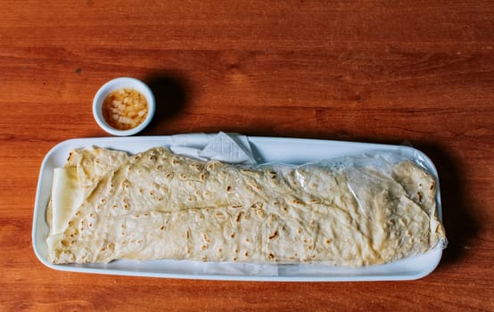 Delicious traditional Nicaraguan quesillo served on wooden table, View of a Nicaraguan quesillo served on table. Top view of Nicaraguan Quesillo on a plate served on wooden table